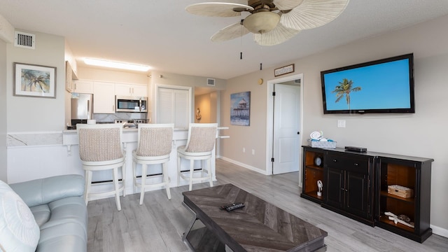 living room with ceiling fan and light hardwood / wood-style flooring