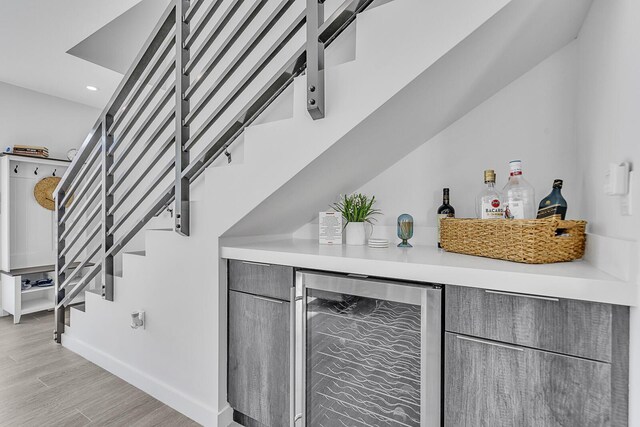 bar with wine cooler and light hardwood / wood-style floors