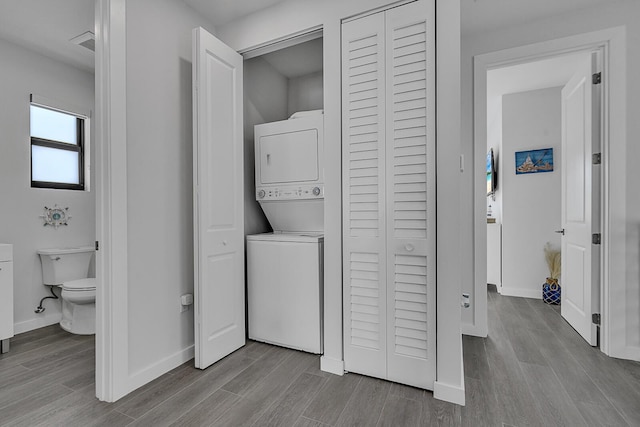 clothes washing area featuring stacked washer and dryer and light hardwood / wood-style floors