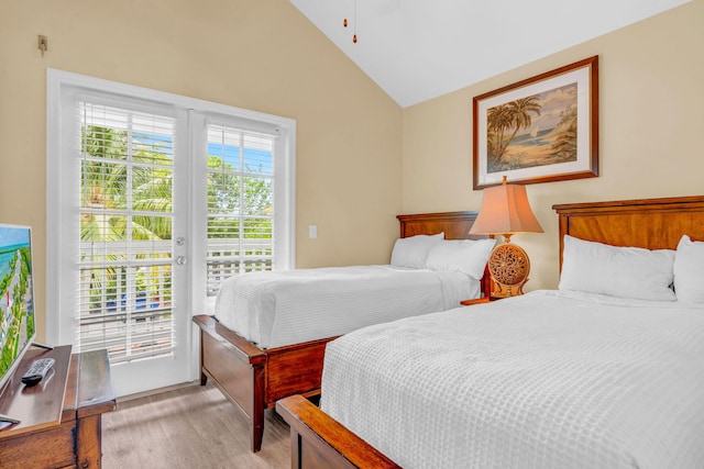 bedroom featuring light hardwood / wood-style floors, vaulted ceiling, multiple windows, and access to outside