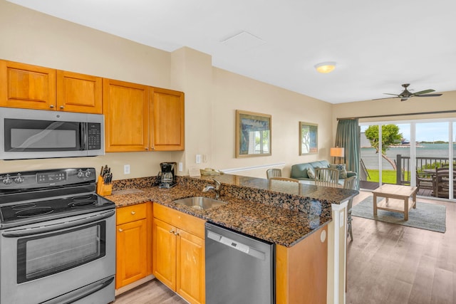 kitchen featuring appliances with stainless steel finishes, sink, light hardwood / wood-style floors, and kitchen peninsula