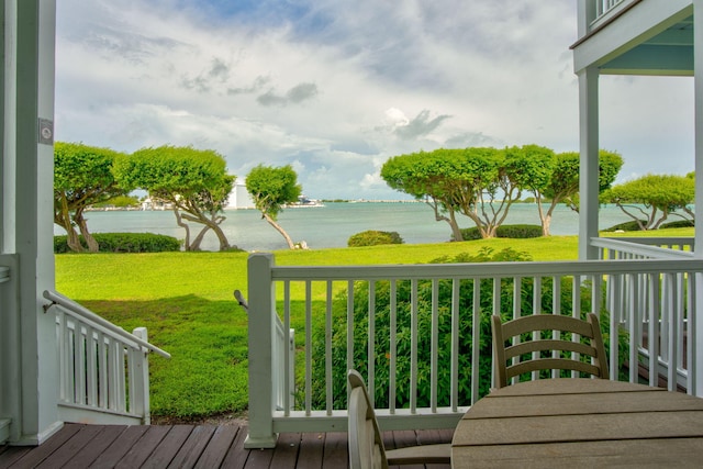 wooden terrace featuring a water view and a lawn