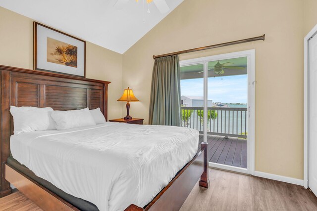 bedroom with vaulted ceiling, a water view, access to exterior, and light hardwood / wood-style flooring