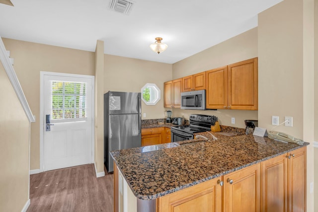 kitchen with stainless steel appliances, plenty of natural light, dark stone countertops, and kitchen peninsula