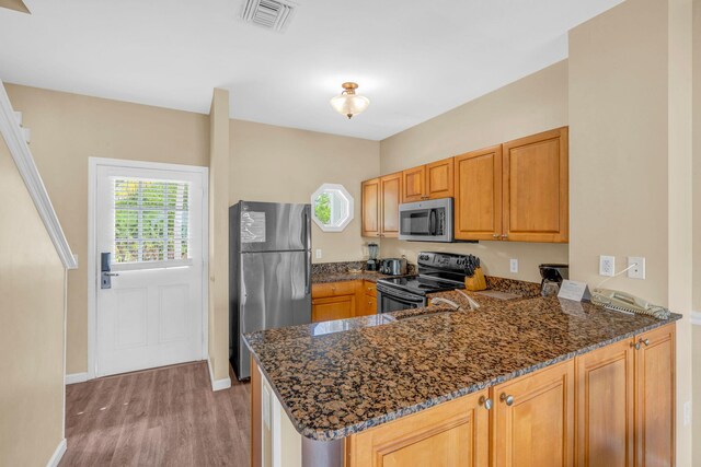 kitchen with stainless steel appliances, plenty of natural light, dark stone countertops, and kitchen peninsula