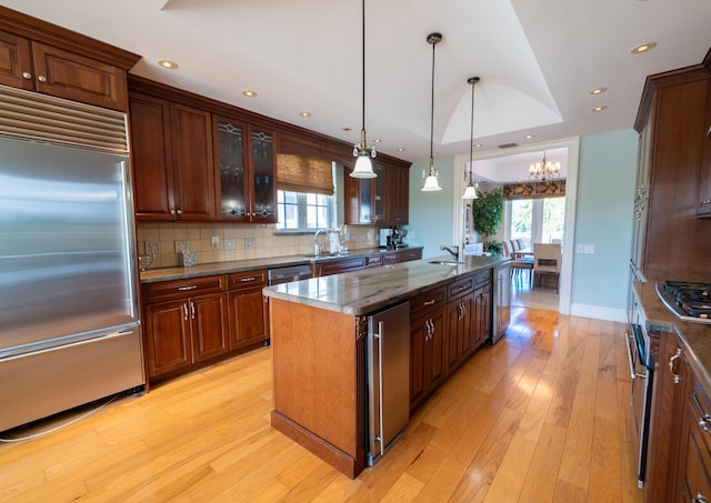33 Cypress Ave, Key Haven, FL 33040 - kitchen featuring stainless steel appliances, a center island with sink, backsplash, light wood-type flooring, and a chandelier