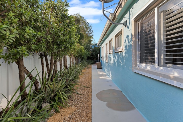 view of side of home with stucco siding and fence