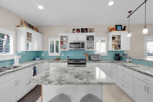 kitchen with backsplash, glass insert cabinets, stainless steel appliances, white cabinetry, and open shelves