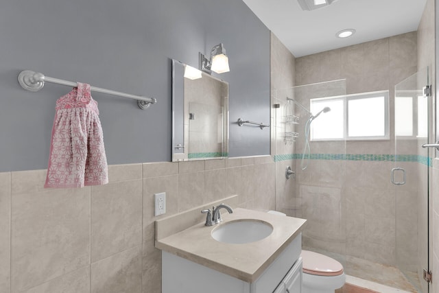 full bath with vanity, tile walls, a shower stall, and toilet