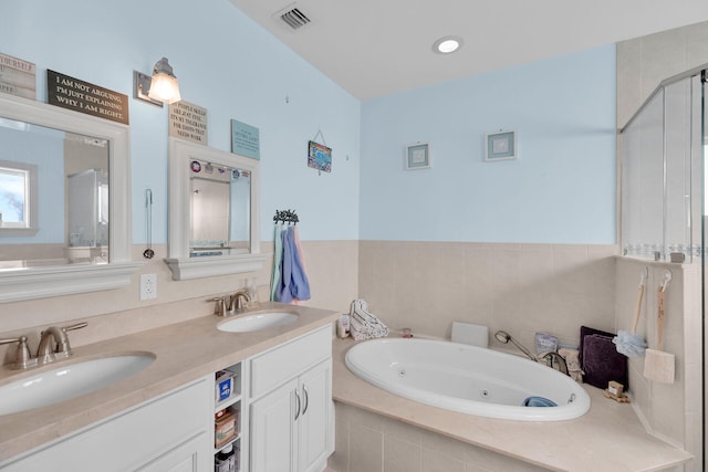 full bathroom featuring double vanity, a jetted tub, visible vents, and a sink