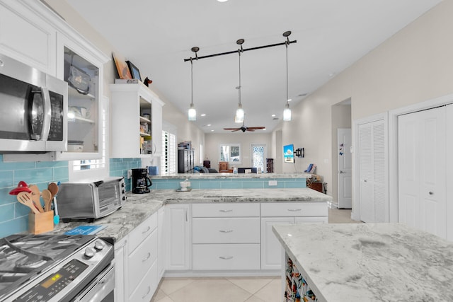 kitchen featuring tasteful backsplash, ceiling fan, light tile patterned floors, a peninsula, and stainless steel appliances