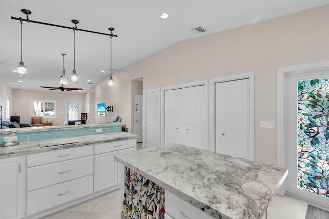 kitchen with a kitchen island, ceiling fan, open floor plan, pendant lighting, and white cabinetry