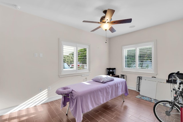 bedroom with multiple windows, ceiling fan, baseboards, and wood finished floors