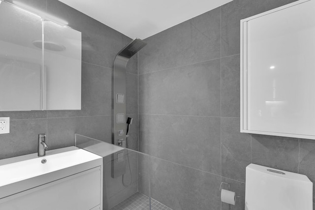 bathroom featuring tasteful backsplash, tile walls, vanity, tiled shower, and toilet