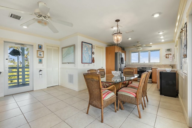 dining area with crown molding, sink, light tile patterned flooring, and ceiling fan