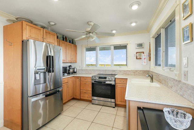 kitchen featuring light tile patterned flooring, appliances with stainless steel finishes, sink, ceiling fan, and crown molding