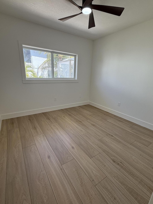 empty room with ceiling fan, baseboards, a textured ceiling, and wood finished floors