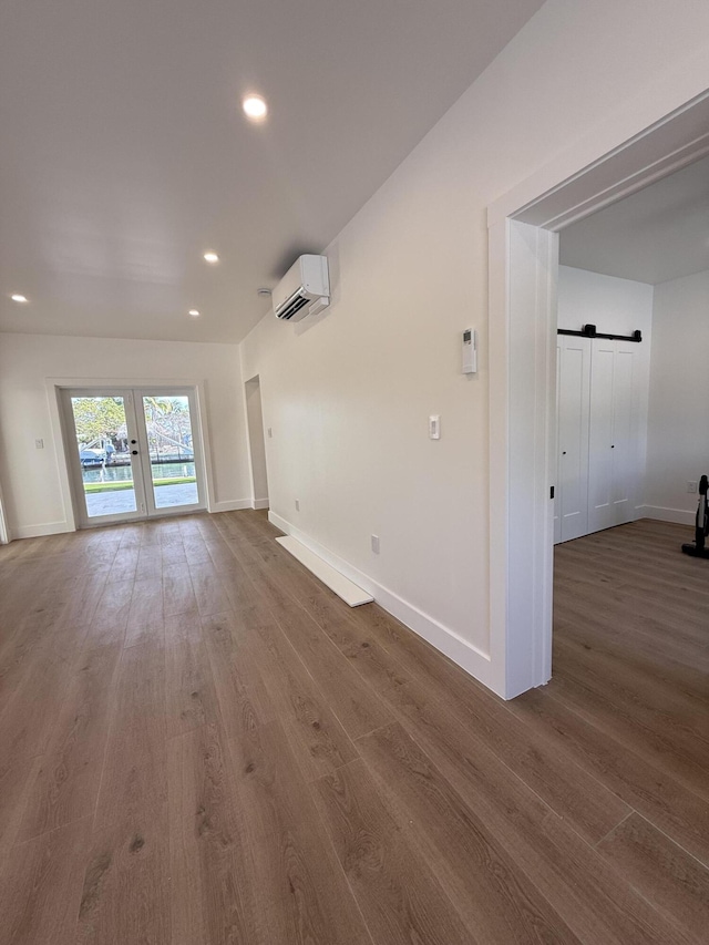 interior space featuring baseboards, a barn door, a wall unit AC, recessed lighting, and wood finished floors