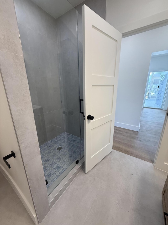 bathroom featuring a shower stall and baseboards