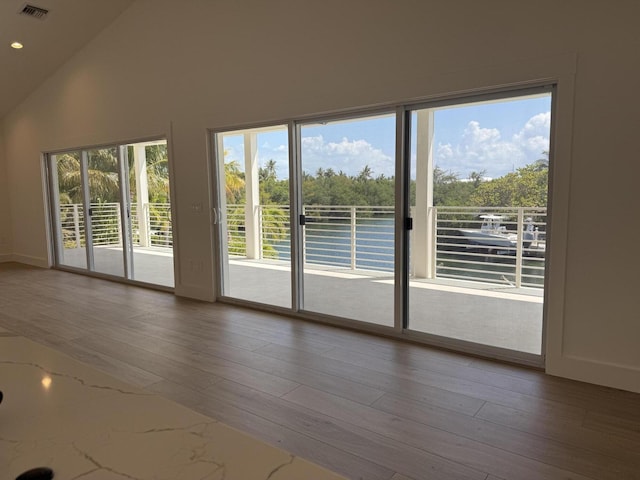 interior space featuring visible vents, baseboards, vaulted ceiling, recessed lighting, and wood finished floors