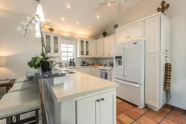 kitchen with white appliances, a sink, a peninsula, glass insert cabinets, and white cabinetry