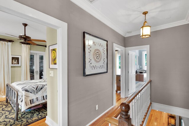 corridor with crown molding, french doors, and light wood-type flooring