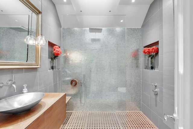 bathroom featuring tasteful backsplash, vanity, a tile shower, and tile walls