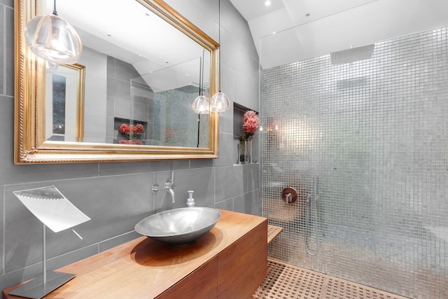 bathroom featuring tile walls, tiled shower, vanity, tasteful backsplash, and vaulted ceiling