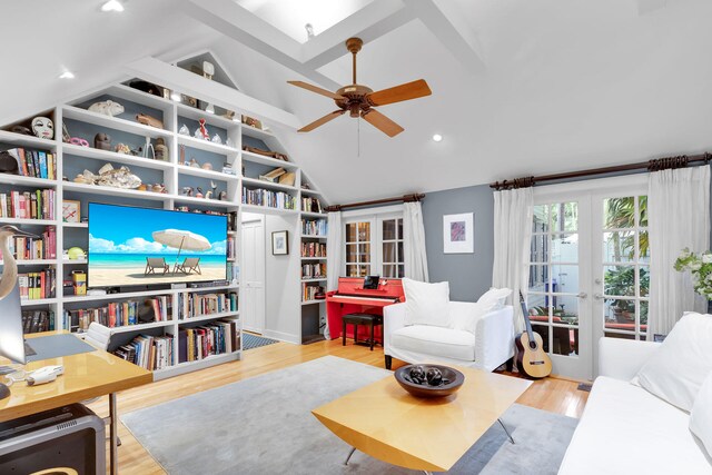 living room featuring ceiling fan, vaulted ceiling with skylight, light wood-type flooring, and french doors