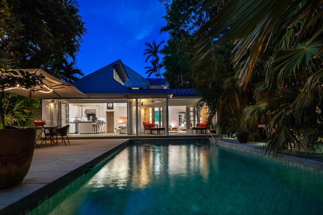 view of swimming pool featuring a bar, ceiling fan, and a patio