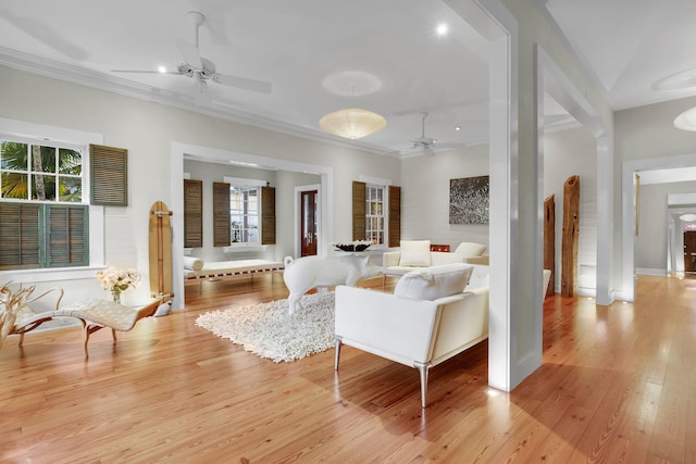 living room featuring crown molding, light hardwood / wood-style floors, and ceiling fan