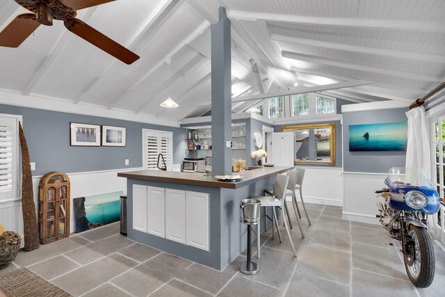 kitchen featuring white cabinets, a kitchen bar, lofted ceiling with beams, and a large island with sink