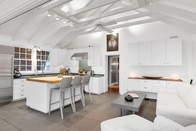 kitchen with a kitchen island with sink, exhaust hood, white cabinets, and built in fridge