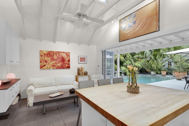 living room featuring ceiling fan, beam ceiling, and a high ceiling