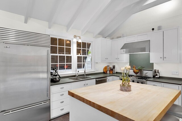 kitchen featuring sink, vaulted ceiling with beams, a center island, stainless steel appliances, and white cabinets