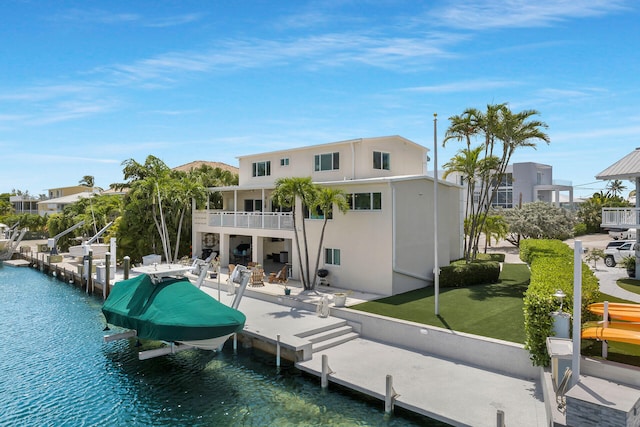 back of house with a yard, a patio area, a balcony, and a water view