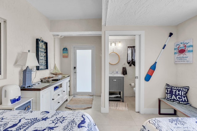 bedroom featuring sink, light tile patterned floors, and a textured ceiling