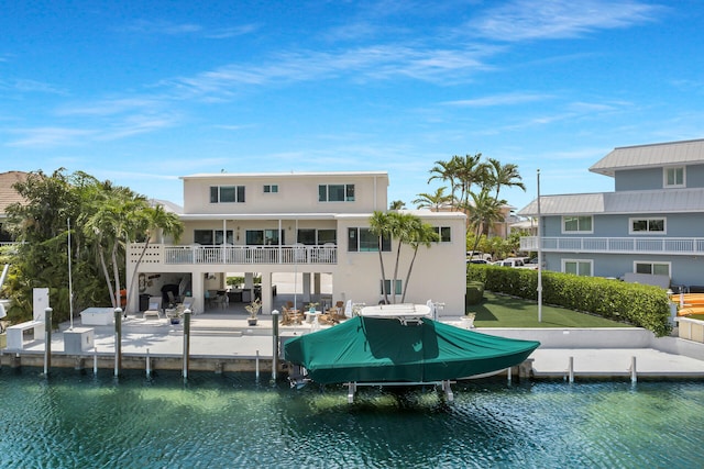 back of property with a water view, a balcony, and a patio area