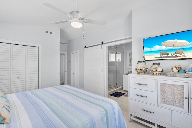 bedroom with lofted ceiling, ensuite bathroom, two closets, ceiling fan, and a barn door