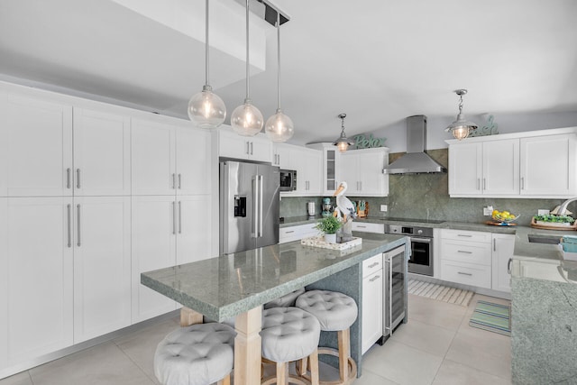 kitchen with appliances with stainless steel finishes, pendant lighting, light stone counters, and wall chimney exhaust hood