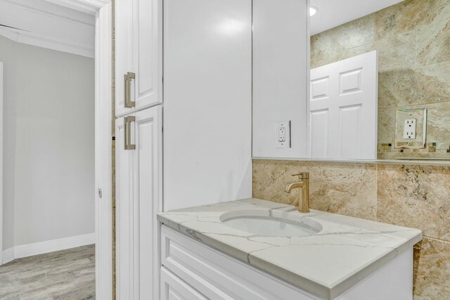 bathroom featuring tile walls, vanity, baseboards, and wood finished floors