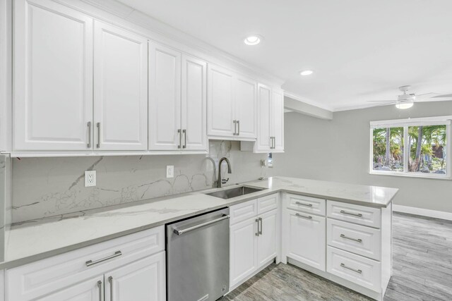 kitchen with light wood-style flooring, a peninsula, stainless steel dishwasher, white cabinetry, and a sink