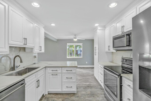 kitchen featuring appliances with stainless steel finishes, white cabinets, a sink, ceiling fan, and a peninsula