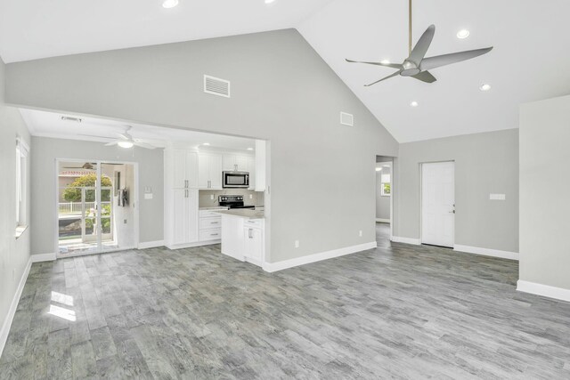 unfurnished living room with baseboards, visible vents, a ceiling fan, light wood-style flooring, and high vaulted ceiling