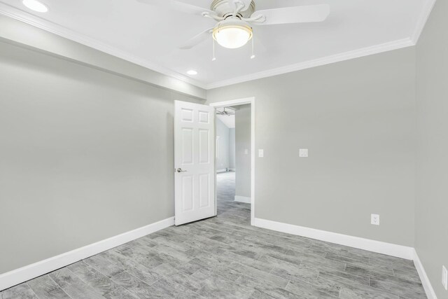 spare room featuring light wood-style floors, ceiling fan, baseboards, and crown molding