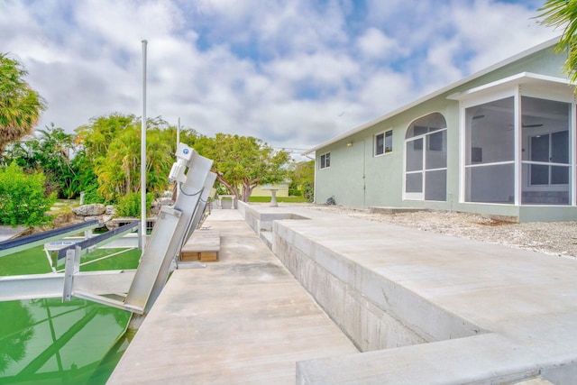 exterior space with a boat dock, boat lift, and a sunroom