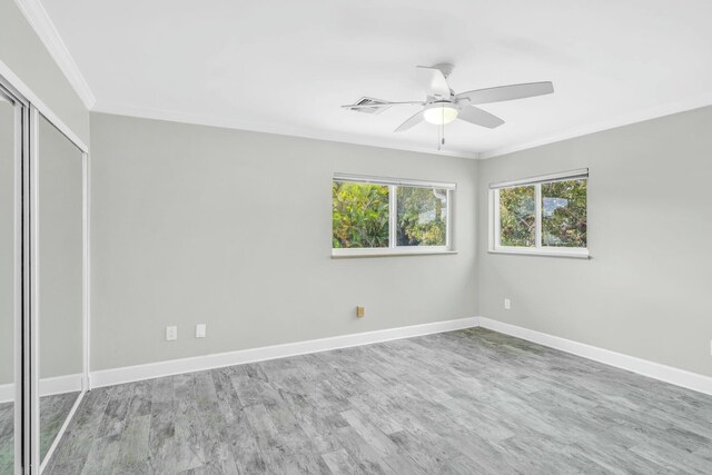 unfurnished room with ornamental molding, light wood-type flooring, visible vents, and baseboards