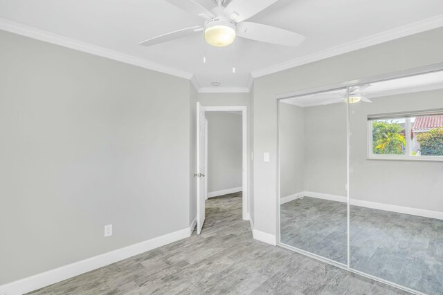 unfurnished bedroom with ceiling fan, light wood-style flooring, baseboards, ornamental molding, and a closet