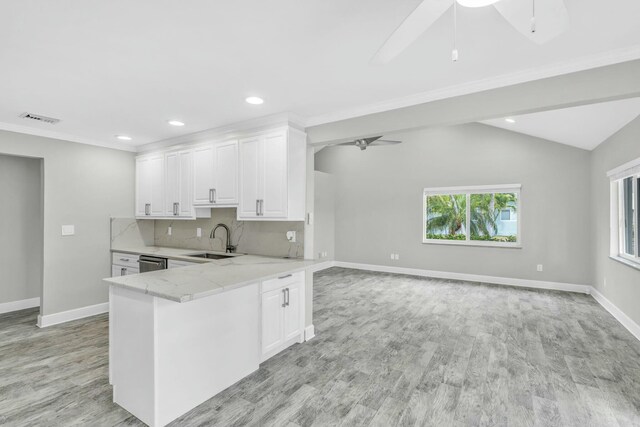 kitchen with light stone counters, visible vents, white cabinetry, a sink, and a peninsula