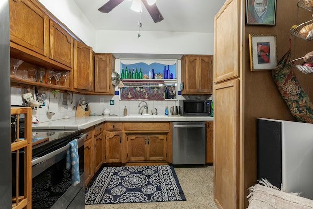 1302 11th St, Key West, FL 33040 - kitchen with stainless steel appliances, a sink, a ceiling fan, tasteful backsplash, and brown cabinets